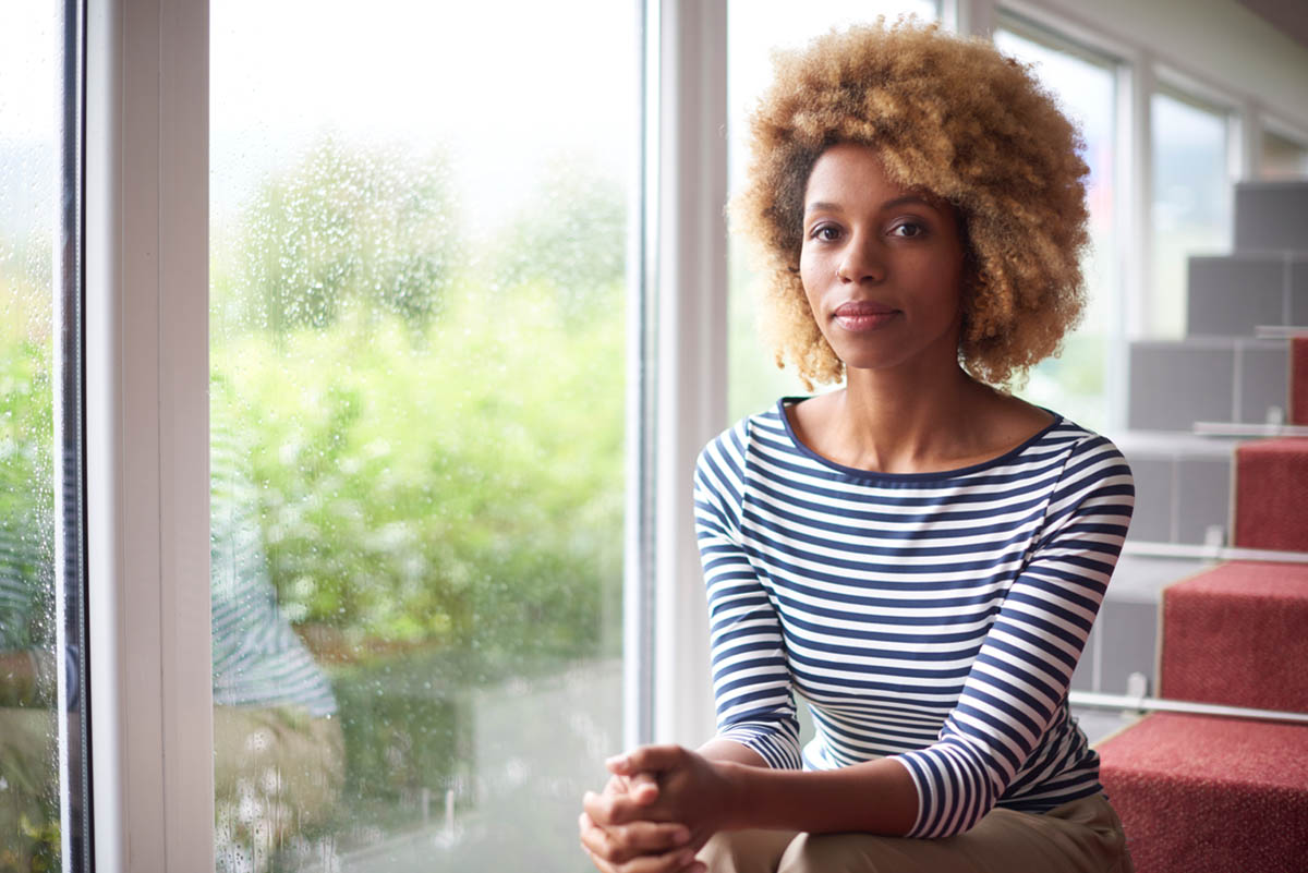 woman with SPMI sits by window