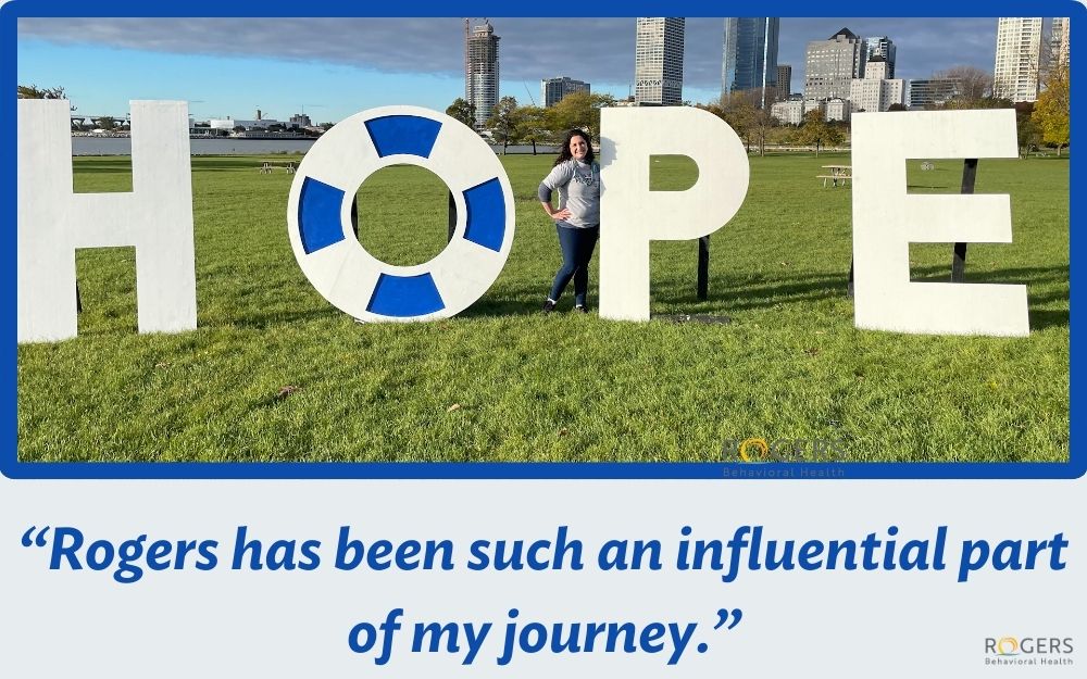 Former patient Marissa poses alongside giant letters that read HOPE