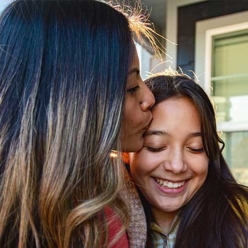 A woman kissing her daughter on the forehead